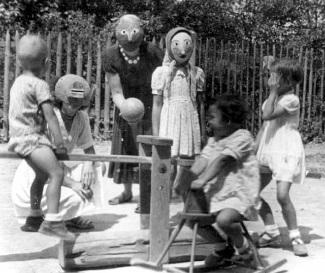 11.JPG - Maria, Halina i Anna w towarzystwie rodziny na podwórku przed szkołą; maski wykonane przez J. Dudka wykorzystywane w przedstawieniach.